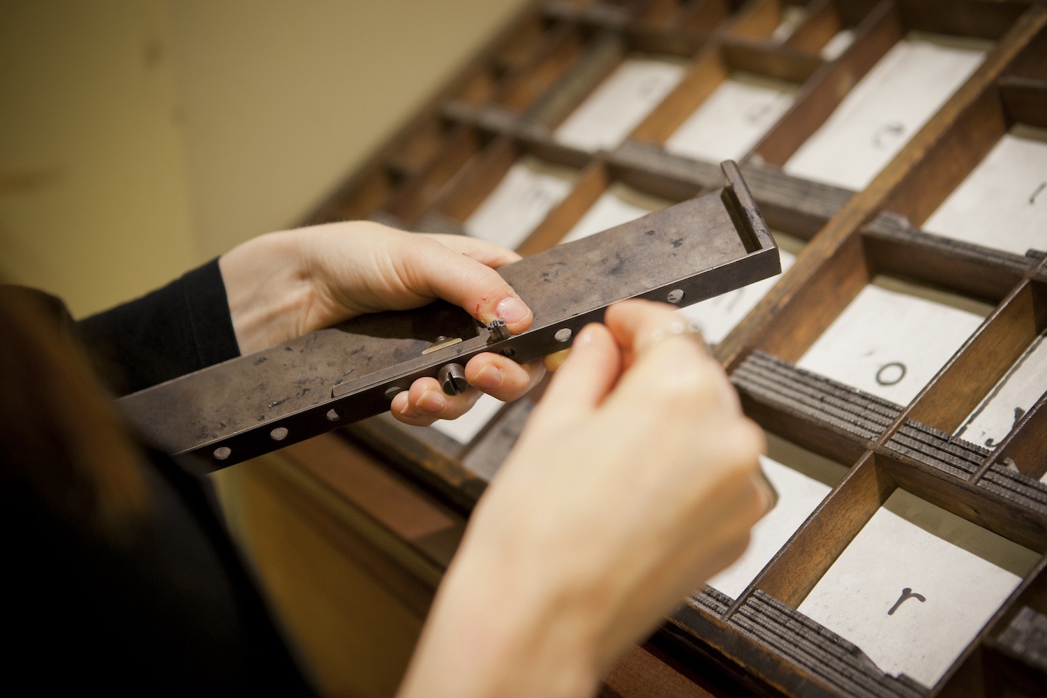 PrintPress5 A woman putting letter pieces into a thin metal tray
