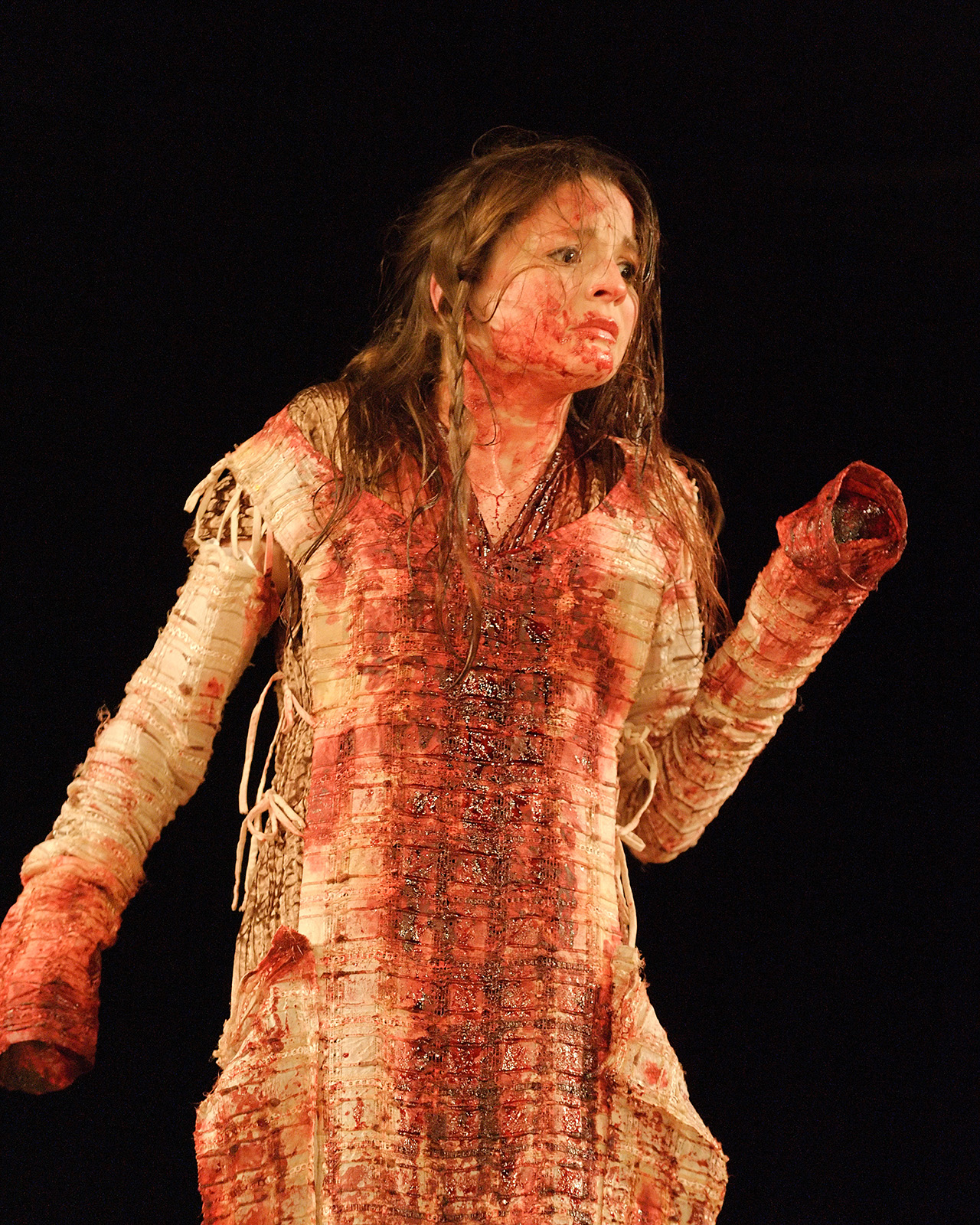 An actor wearing a white dress covered in blood, with their hands severed (faked).