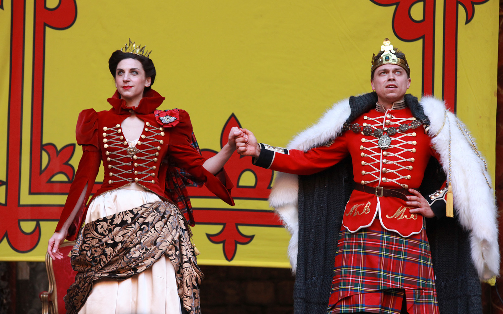 Macbeth and Lady Macbeth dressed in royal garments hold hands