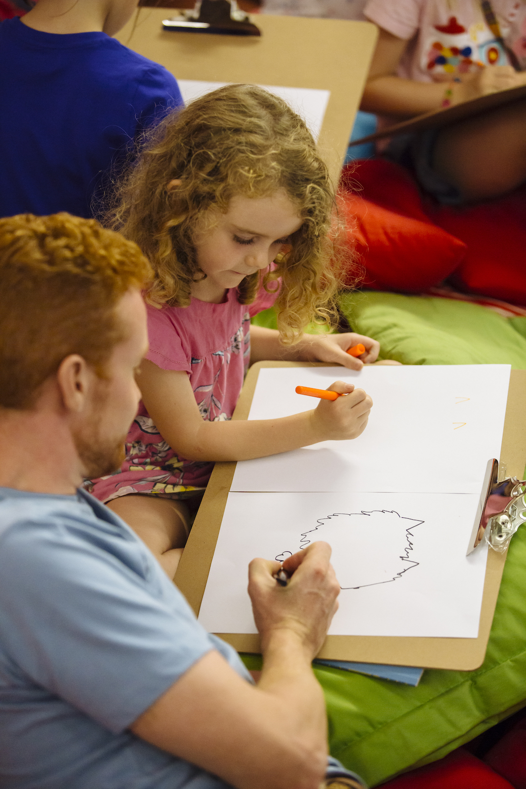 An adult and a child draw on pieces of paper together