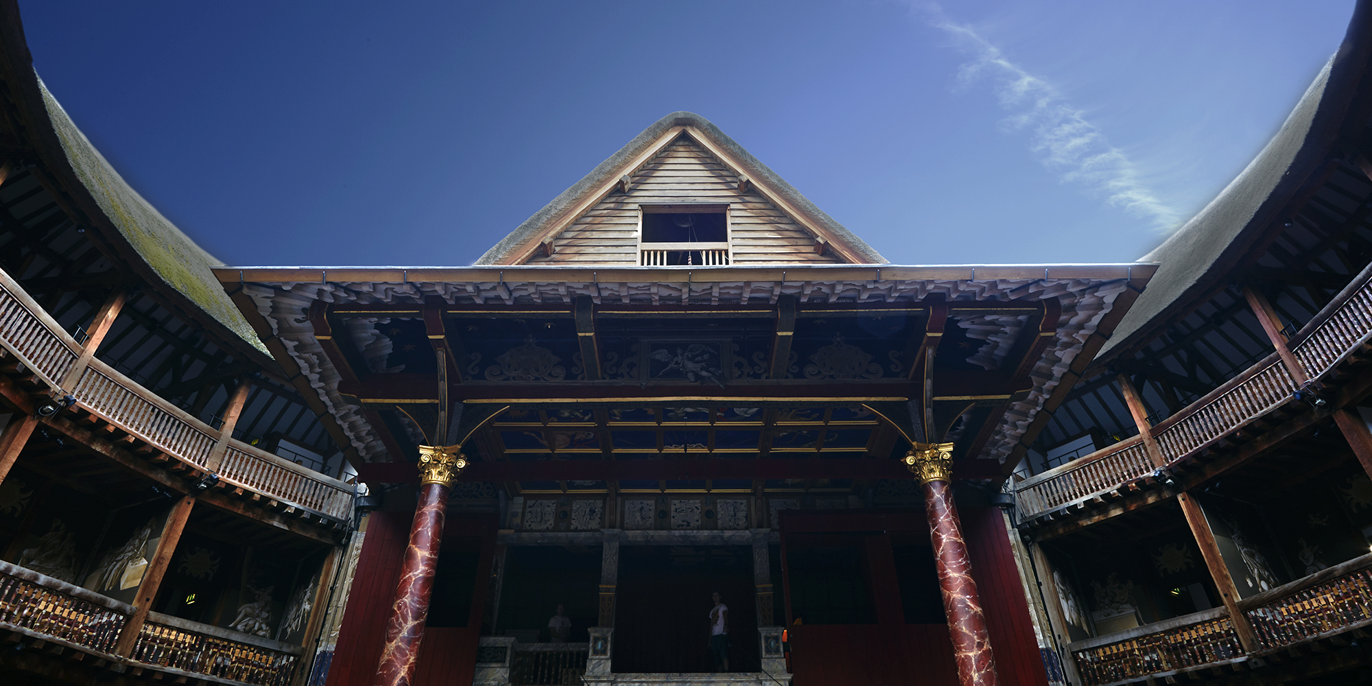 Globe Theatre Summer Shakespeare's Globe A blue sky over the pointed roof of a timber structure theatre.