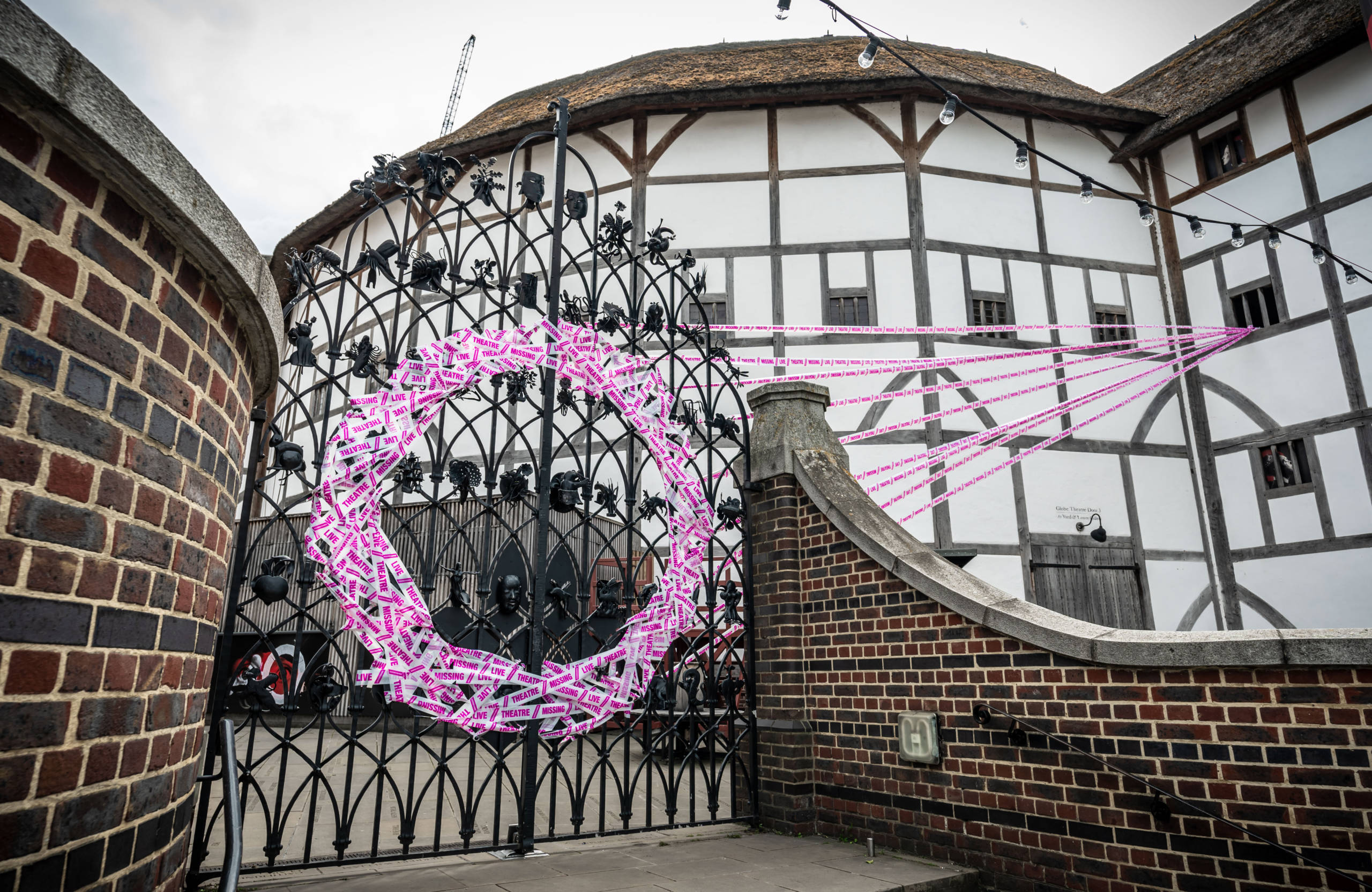 White and pink tape forms a circle on a set of iron gates.