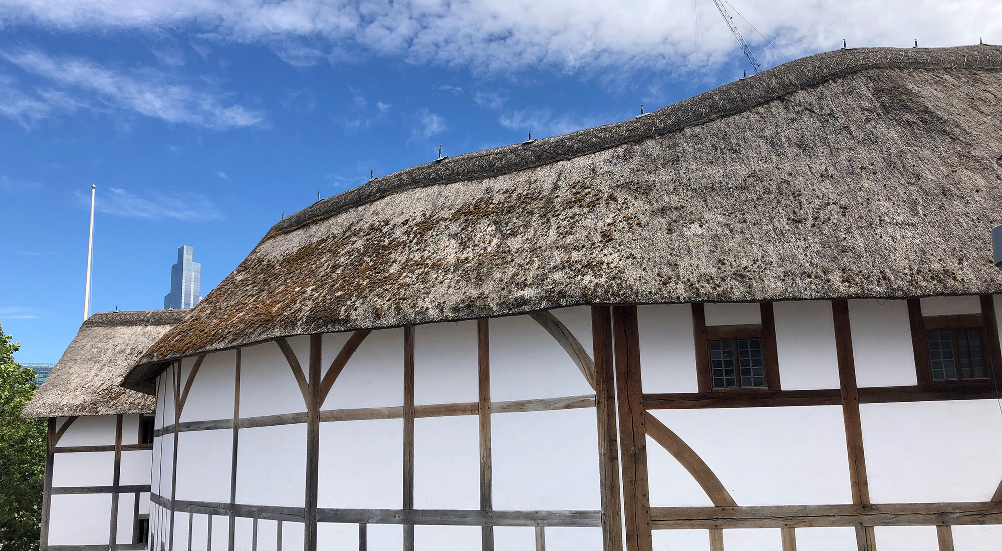 Globe Theatre Summer 2020 A side view looking at a white wattle and daub theatre, with a blue sky above