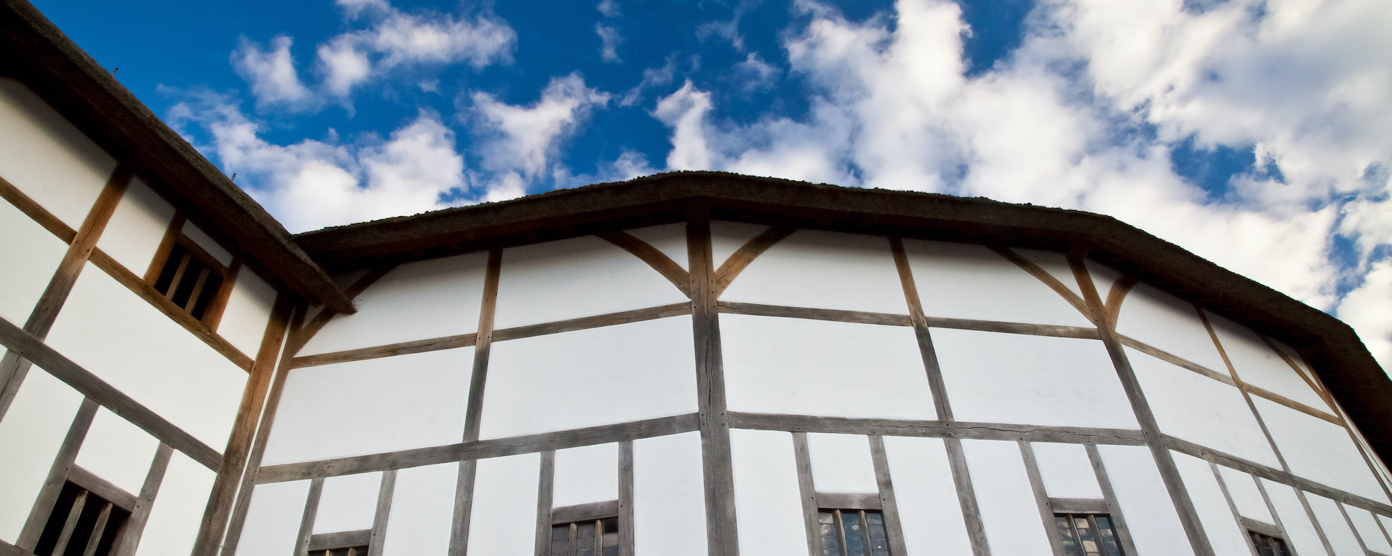 Globe Theatre Facts and Figures A timber-framed building in front of a blue sky