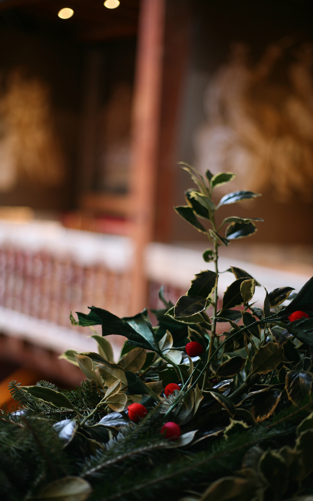 A close up of a holly wreath wrapped around wooden banisters.