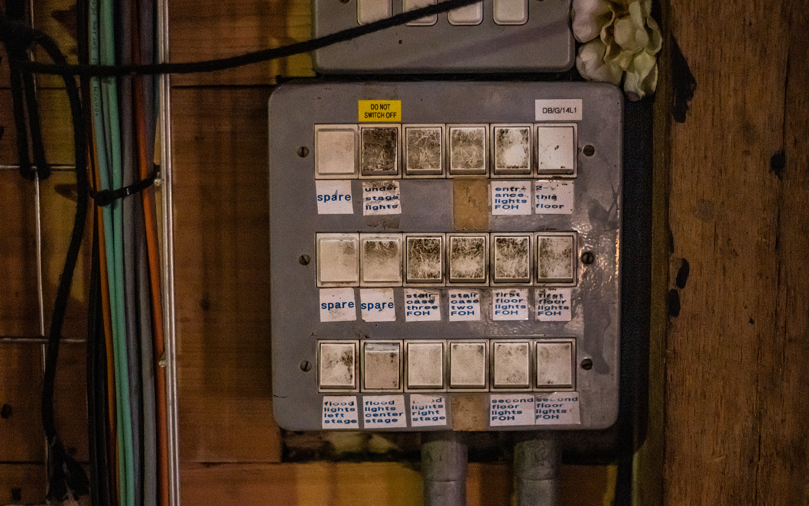 Heaven to Hell Globe Magazine Article Greg Morrison Lightswitches A grey electrical box, with lightswitches covered in homemade labels