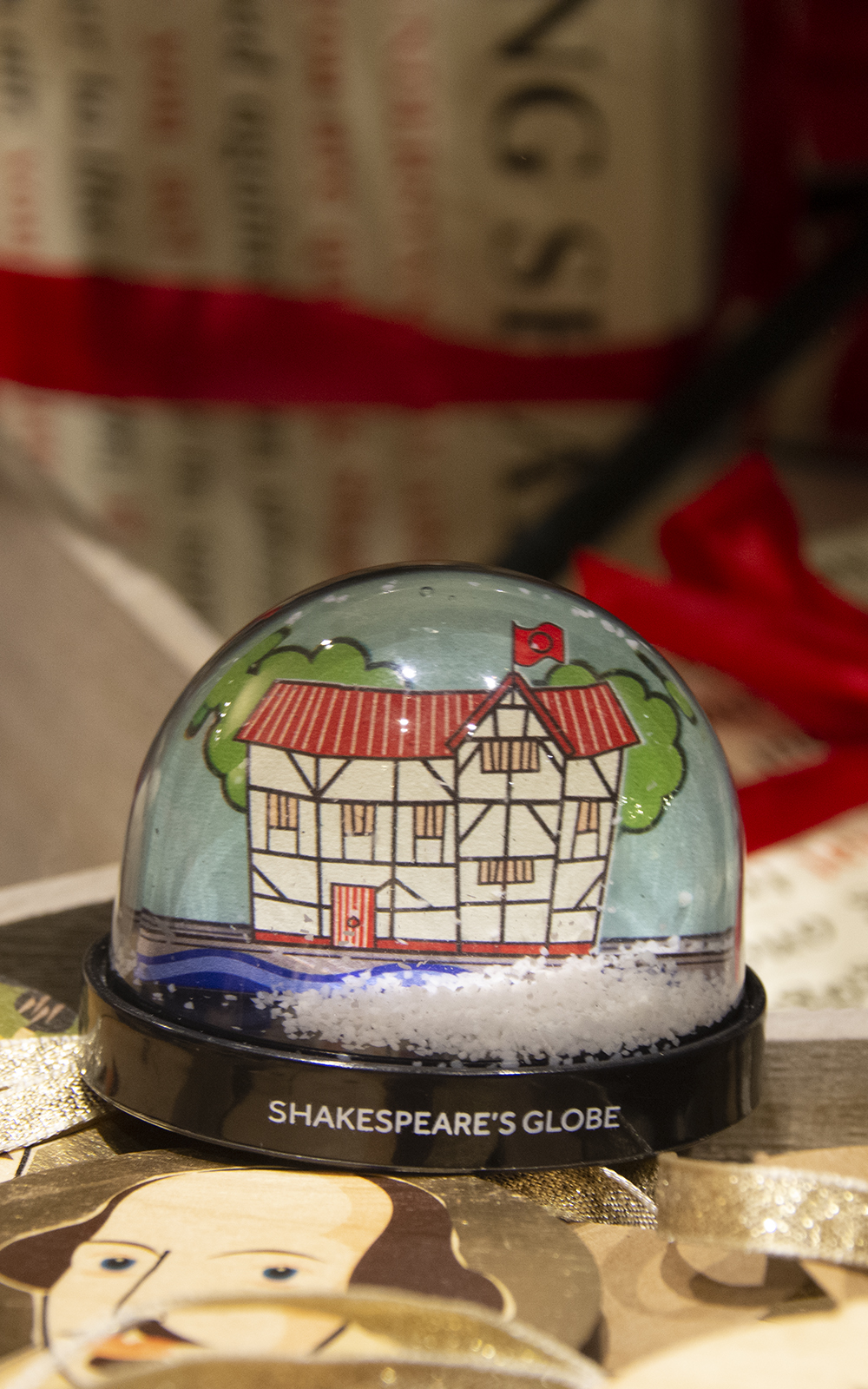 Globe Magazine Article Snowglobe Shop A snowglobe with a cartoon of a round wooden theatre as its background