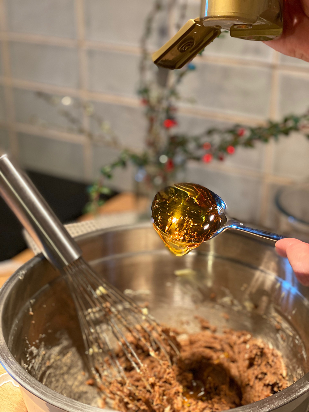 A spoon of golden syrup is dropped into a brown gooey mixture.