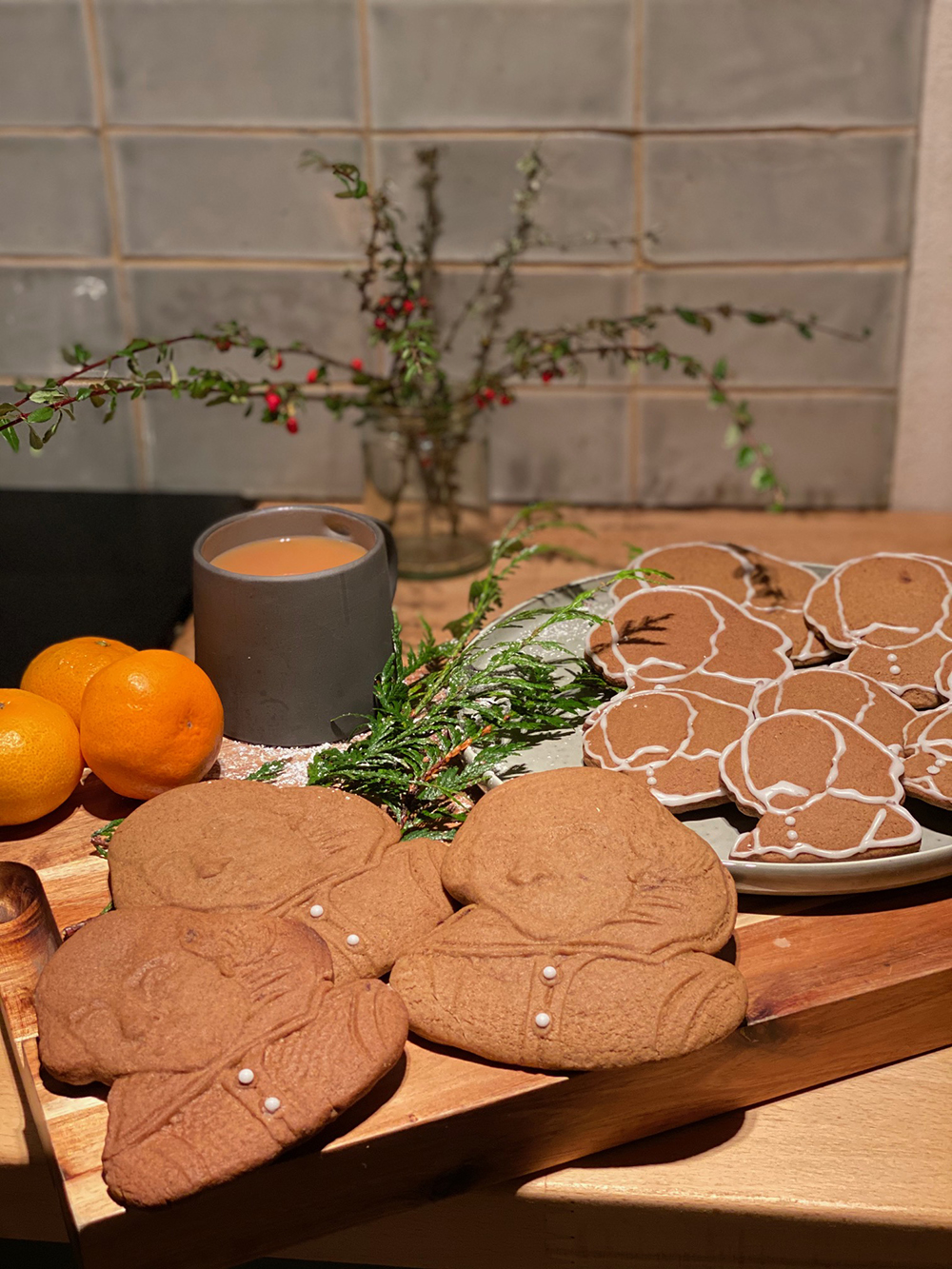 Gingerbread biscuits in the shape of Shakespeare's face rest on a plate with a mug of tea.