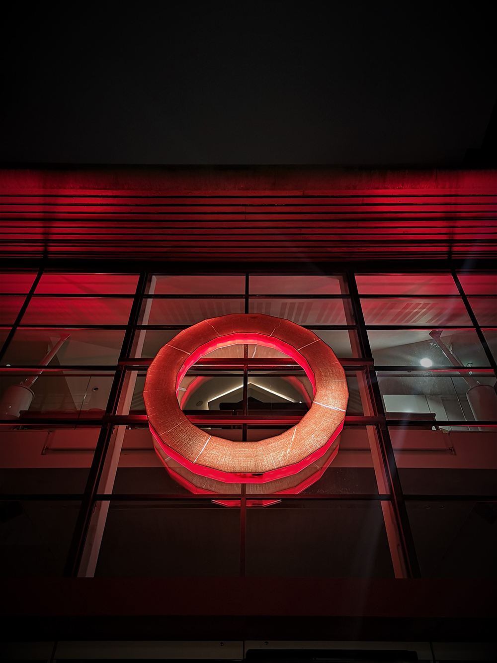The red circular logo of Shakespeare's Globe is backlit by red light.