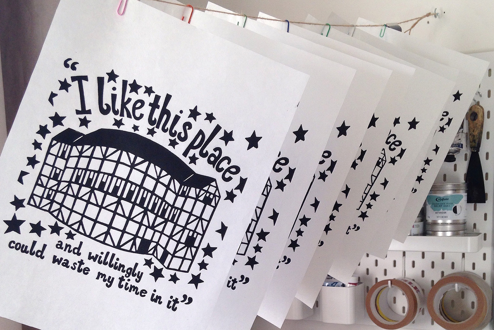 Prints hanging to dry A series of prints hang to dry, with an illustration of the Globe Theatre and the text: I like this place and willingly could waste my time in it