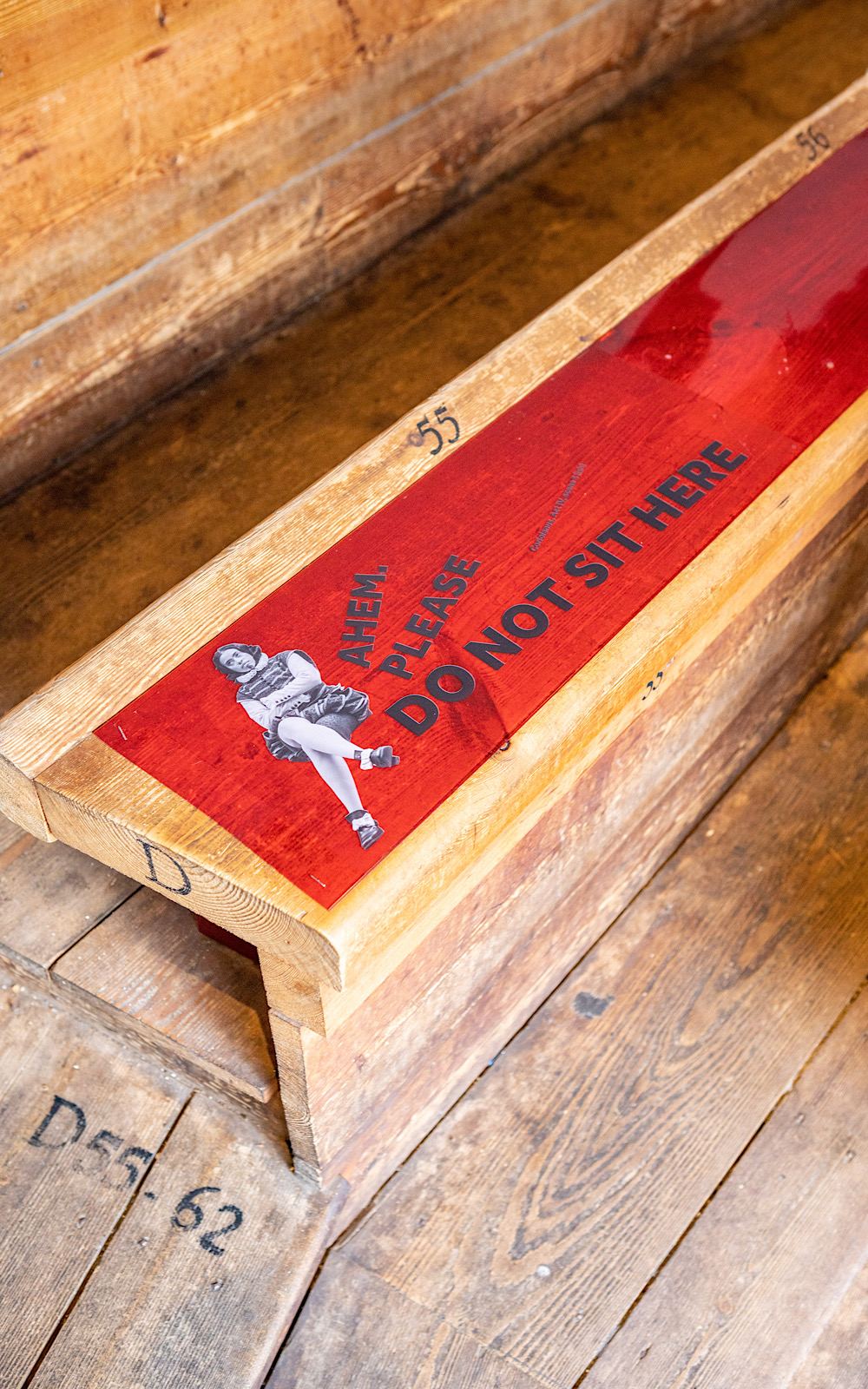 Covid Coronavirus Shakespeare’s Globe Pete Le May 2021 A wooden bench has a sticker on it which reads the words ‘ahem, please do not sit here’