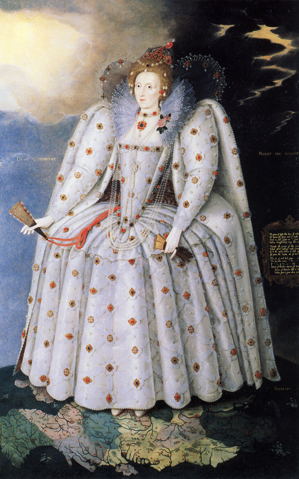 Portrait of Elizabeth I. Her face is painted white and her red hair is piled high in curls, beads and jewels adorning her head. She wears a sumptuous white gown adorned with flowers, her right hand holding a fan and her left holding a pair of gloves. She stands on a map of the world.