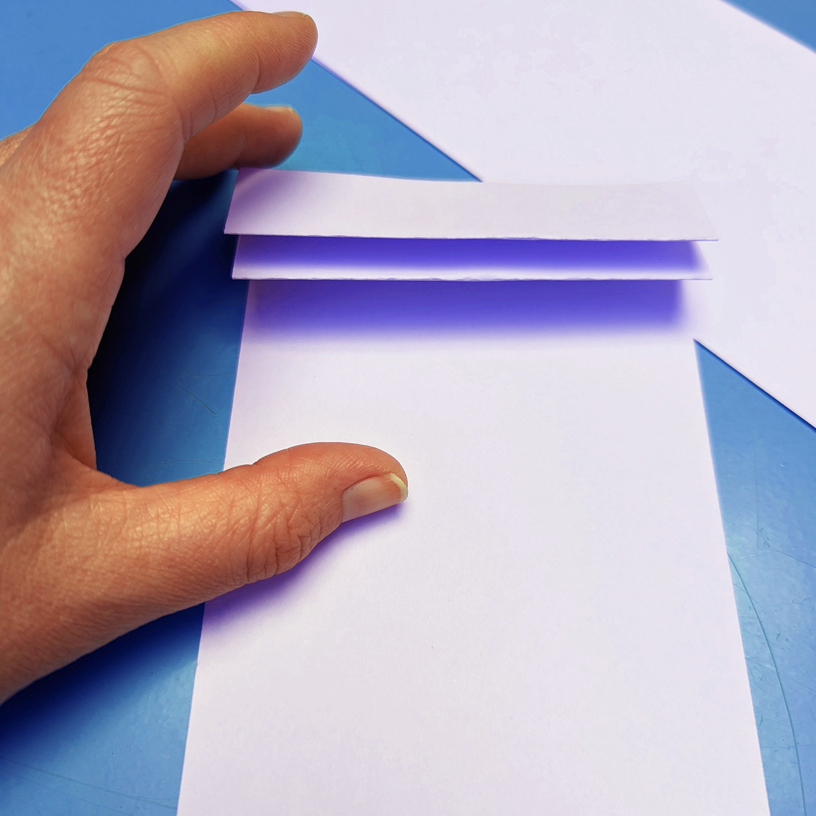 A hand pleating a sheet of paper.